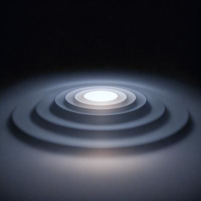 The primary subject of the image is a large, round, white light source, possibly a light bulb or a light fixture, located in the center of the scene. The light source appears to be illuminating a dark, circular area, creating a contrast between the light and the darkness. The setting is a dark room, and the visual style is a close-up of the light source, emphasizing its size and brightness. The colors and mood of the image are predominantly dark, with the white light source standing out